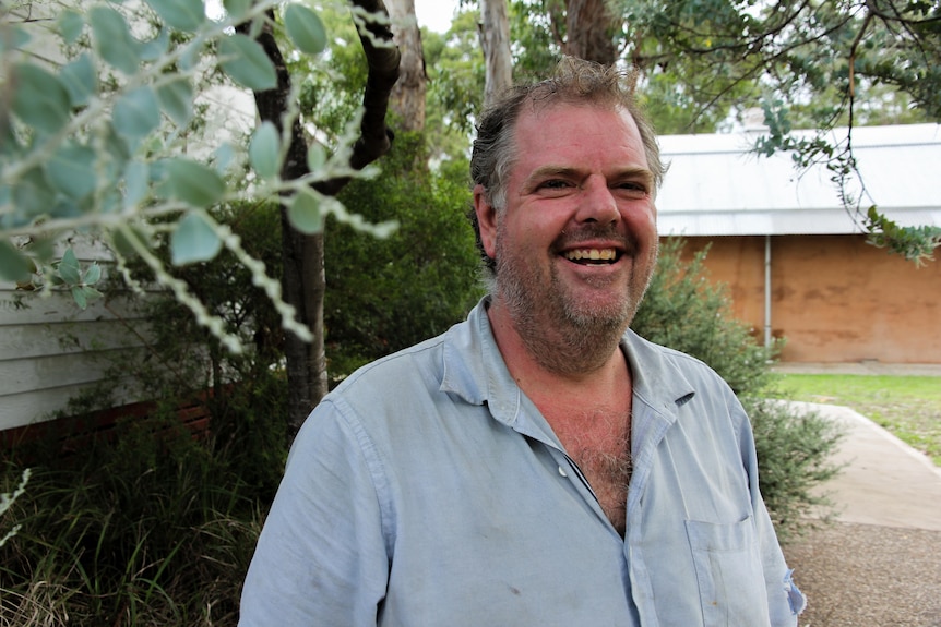 A man standing in front of a wattle tree
