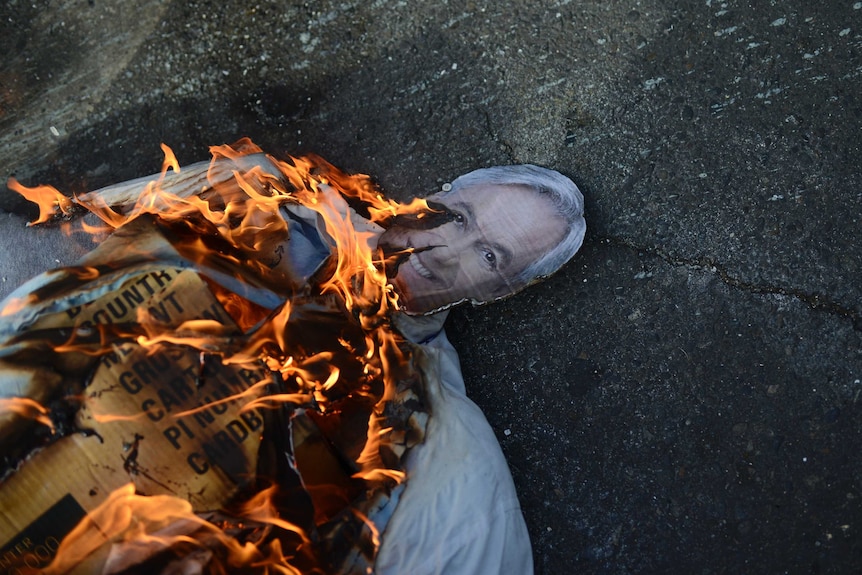 A cut-out depicting Chile's President Sebastian Pinera burns on the pavement during anti-government protests in Valparaiso