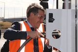 Man in high-vis holds hose and nozzle as he refuels a truck