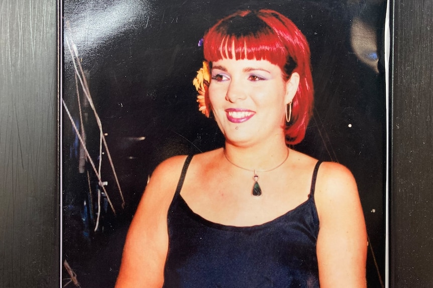 A woman with bright-red dyed hair smiles for the camera