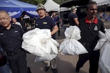 Forensic policemen carry body bags at the site of human trafficking camps