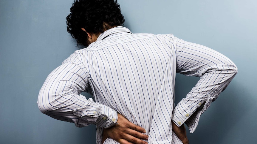 A man leaning over with his hand on his back - expressing pain