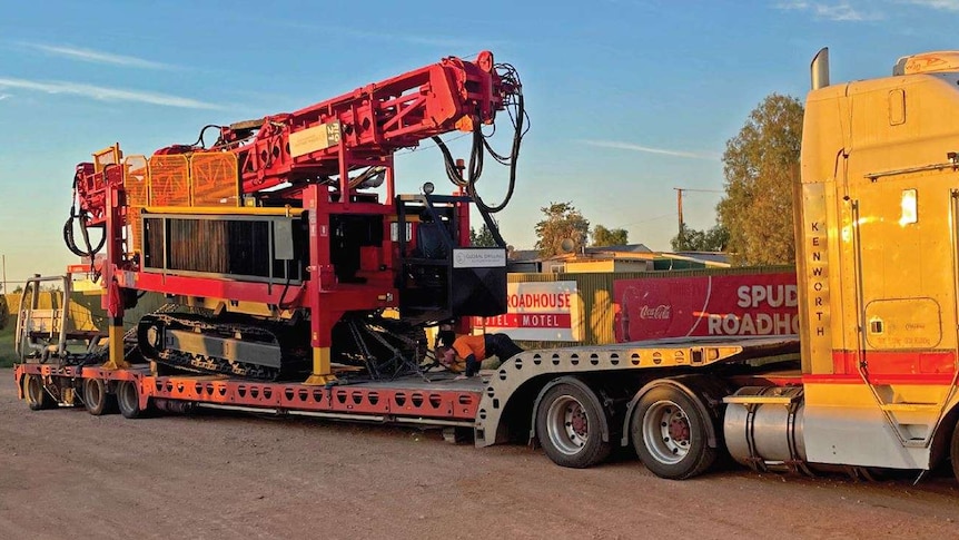 A crane-like machine on the back of a flatbed truck.