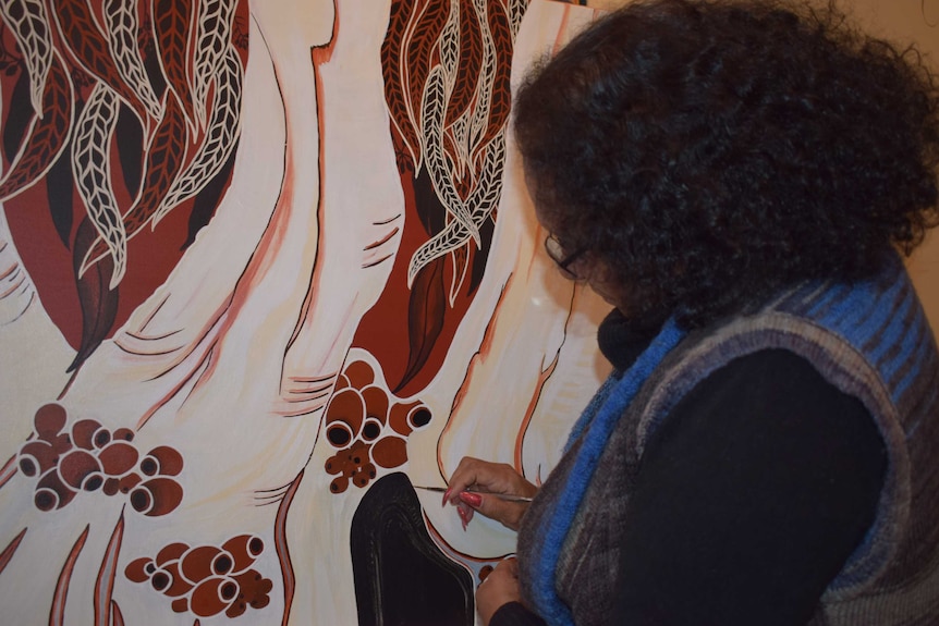 A woman painting a picture of trees.