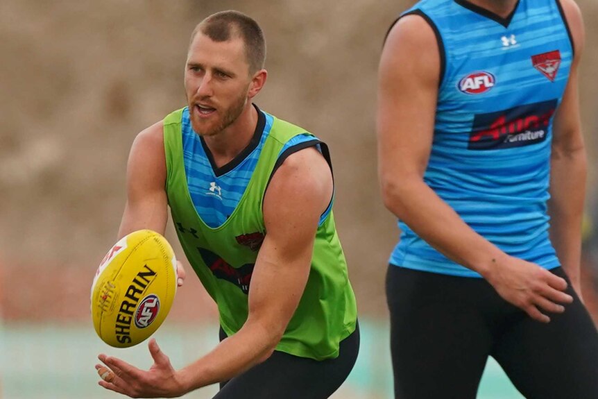 An Essendon Bombers AFL player handballs during a training session in Melbourne.