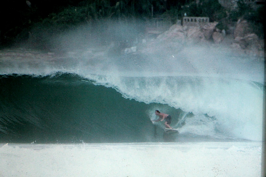 1996 man surfing big barrels with cliffs and city behind