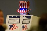 A man wearing a USA top hat casts his vote.