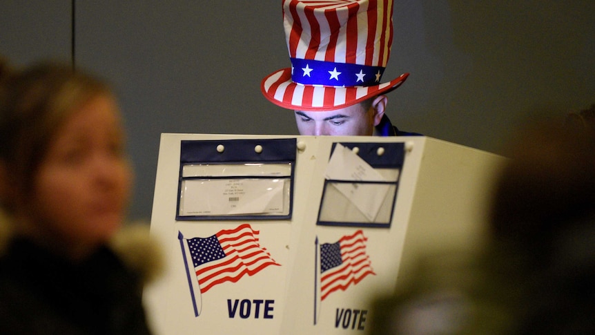 A man wearing a USA top hat casts his vote.
