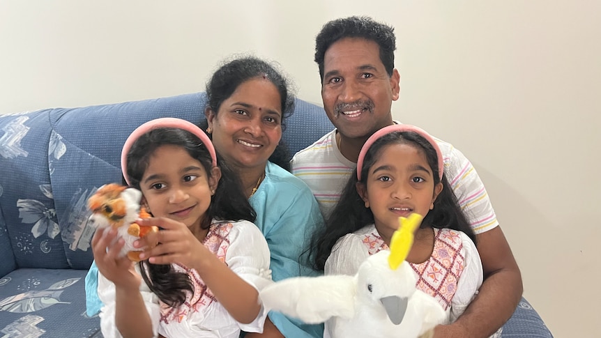 A family sits happily on the couch. 