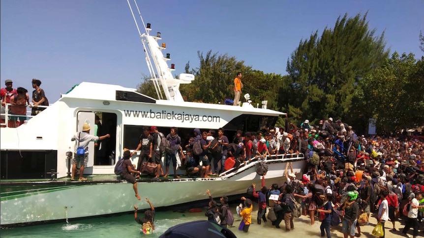 People crowd to load a boat on a the Gili Islands