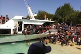 People crowd to load a boat on a the Gili Islands