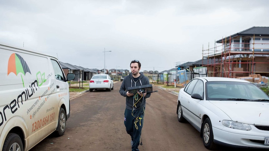 Matt carries a television box into the house.