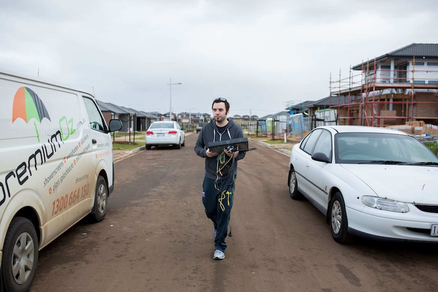 Matt carries a television box into the house.