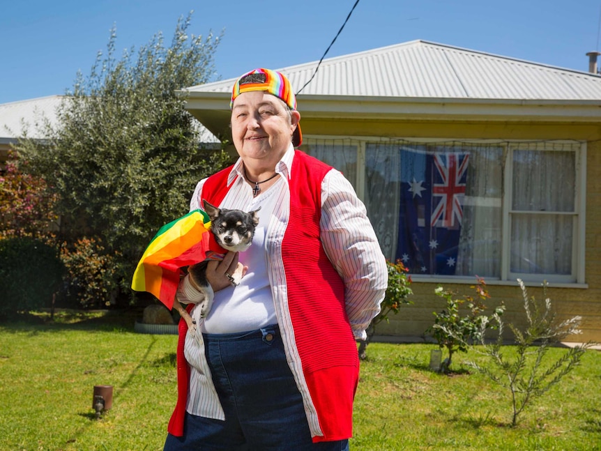 Helen and her dog Colin, wearing a rainbow flag