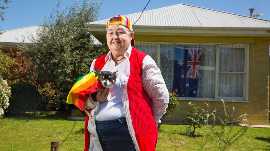 Helen and her dog Colin, wearing a rainbow flag