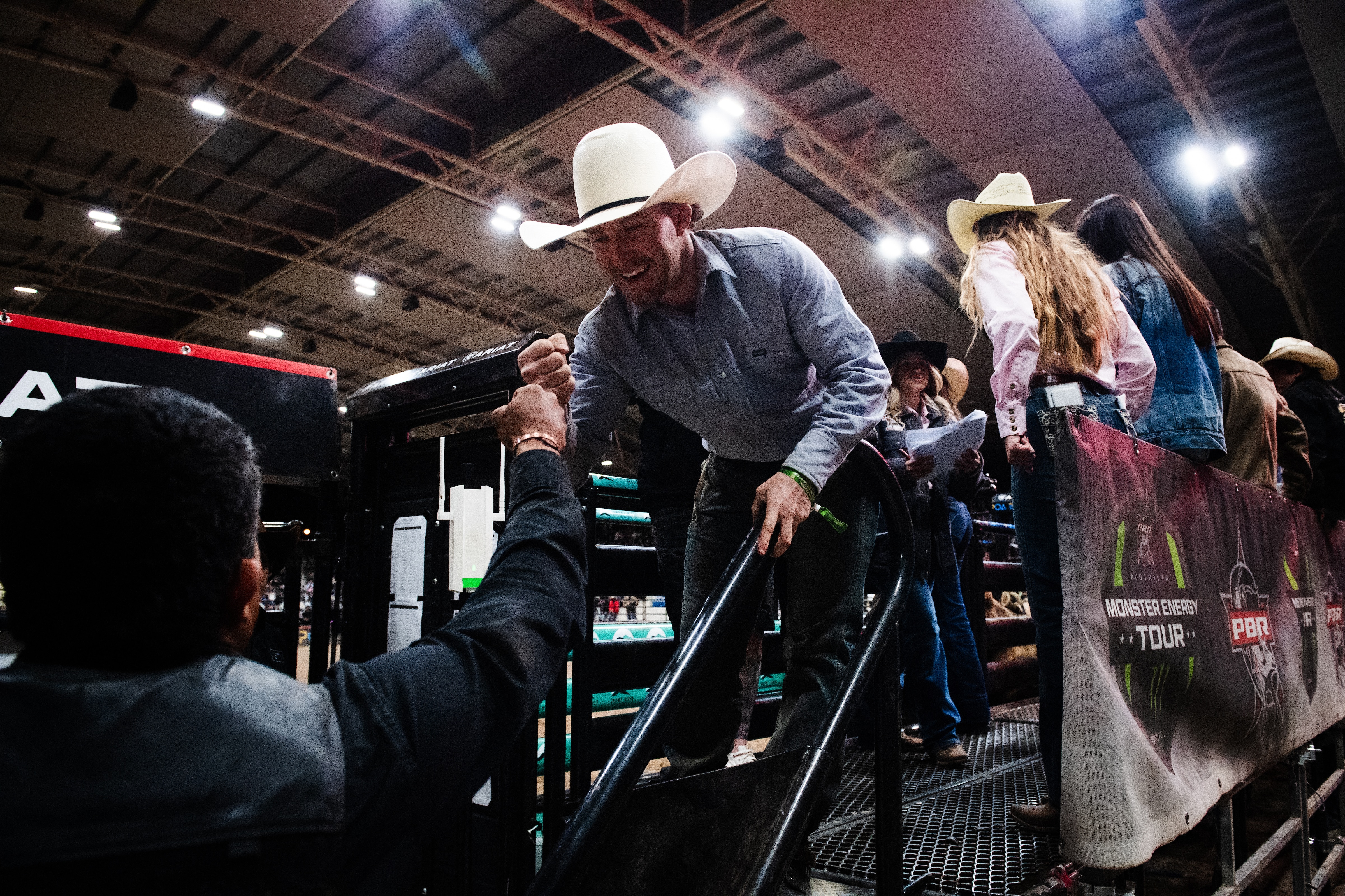 A man in a cowboy hat bumps first with another man. 