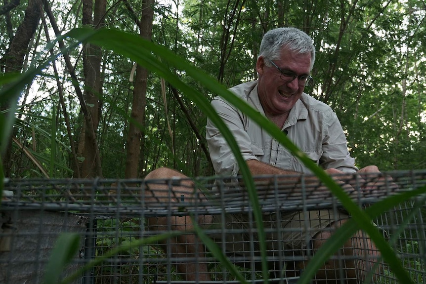 A photo of an ecologist fixing shut a metal trap.