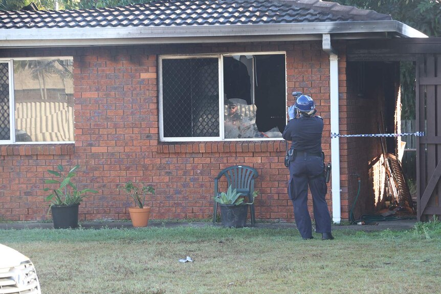Police officer takes photos of a fire-damaged low-set duplex at Fisher Street in Bucasia in Mackay.