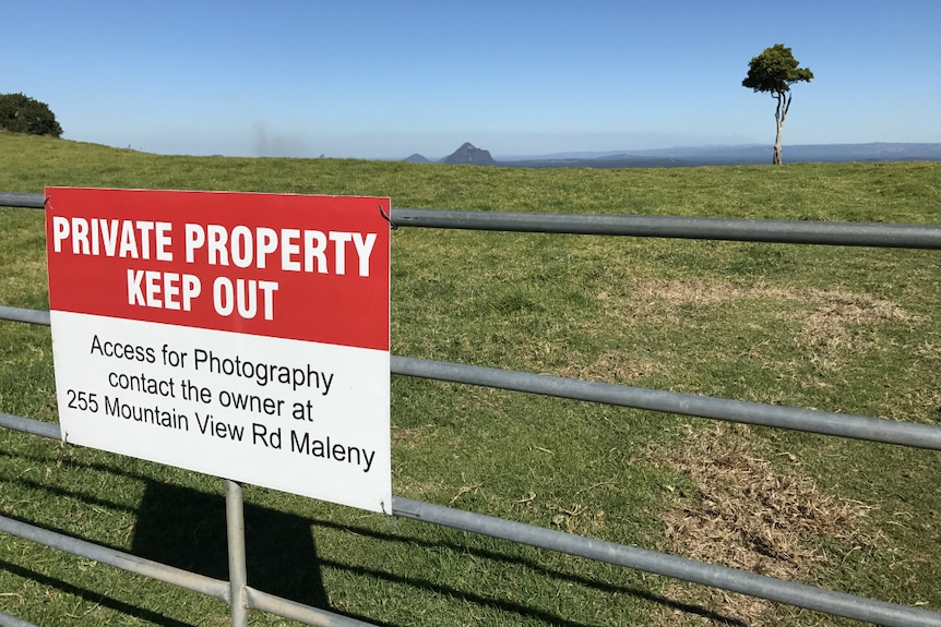 Private property keep out sign on the gate with the tree behind it.