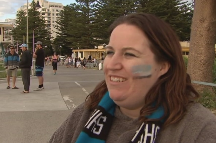 A Sharks fan, still wearing her face paint and scarf celebrates her team's grand final win.