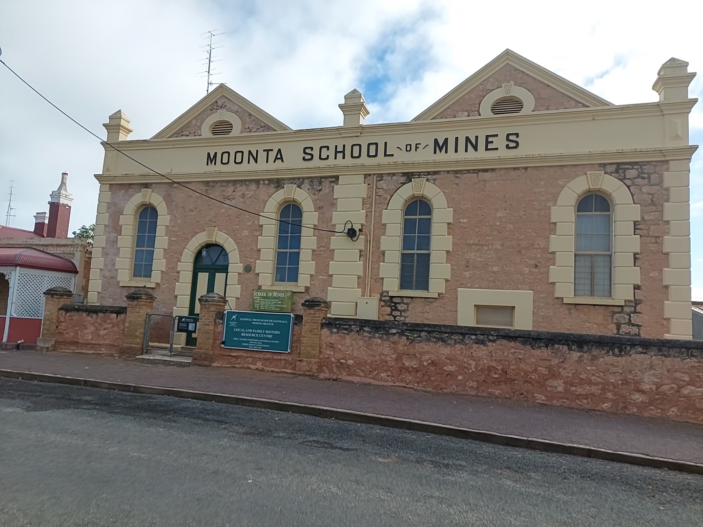 A sandstone building with four windows, signage above door reading Moonta School of Mines