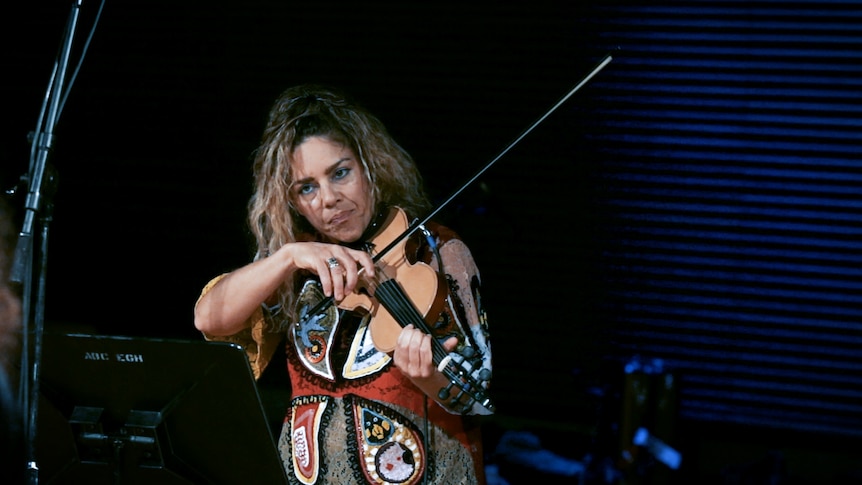 A woman plays violin in a recording studio.
