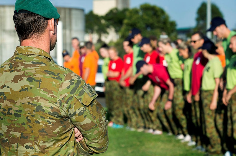 An army soldier watches athletes and coaches train