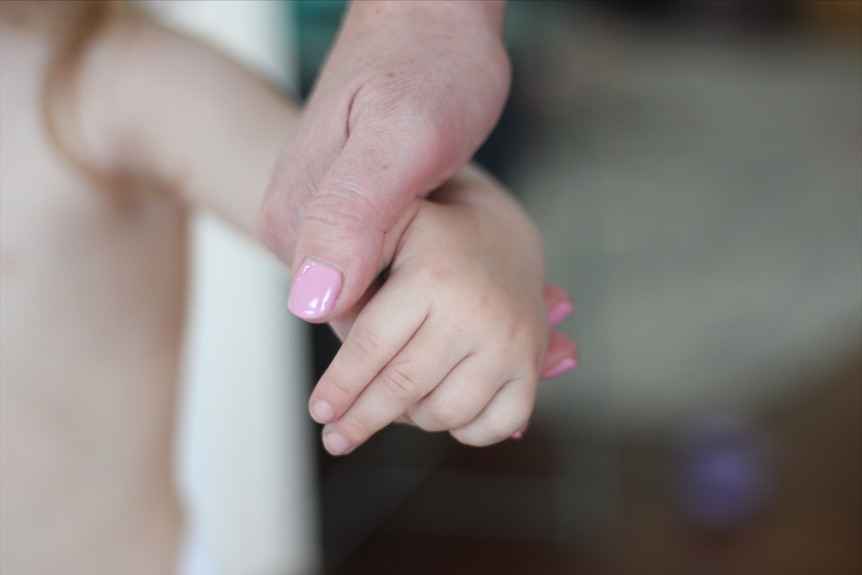 A close up of a big hand holding a little hand