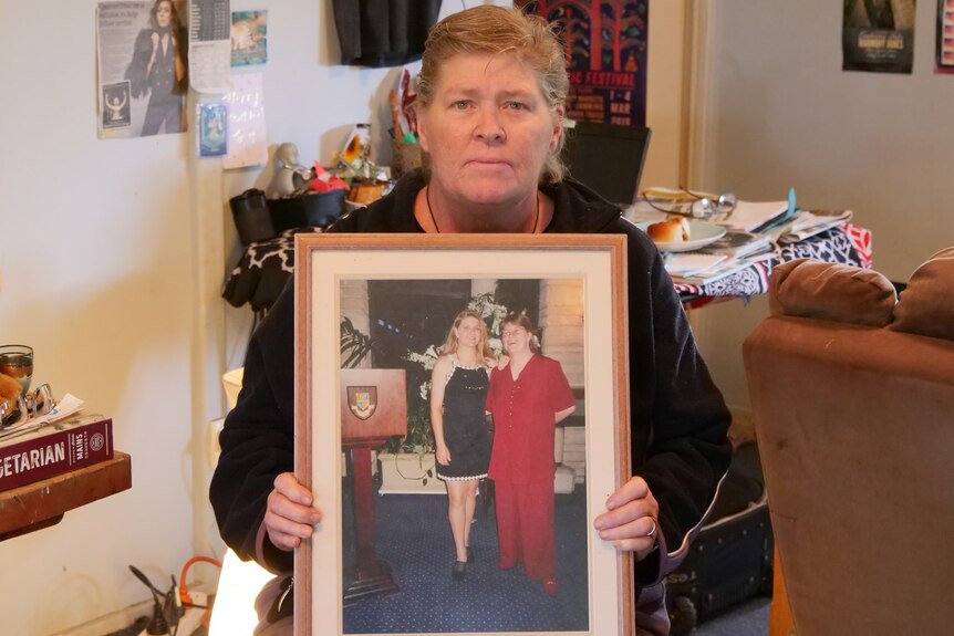 Lee Rimmer holds a large framed photograph of her and her sister Jane Rimmer.