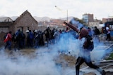A man enveloped in tear gas, throws a cannister at a group of people
