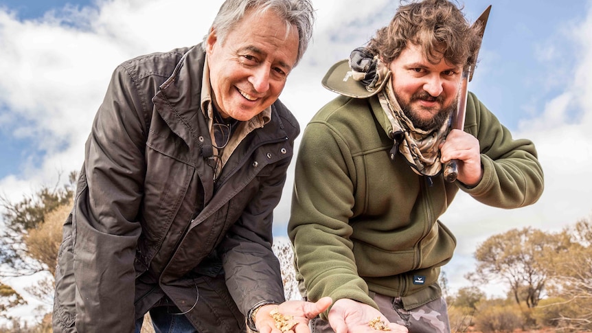 A father and son holding some small gold nuggets.