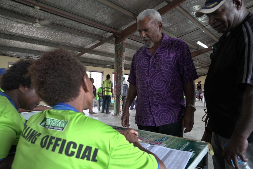 Sir Mekere Morayta wears a purple shirt at a polling booth and looks frustrated as he learns his name is not on the roll