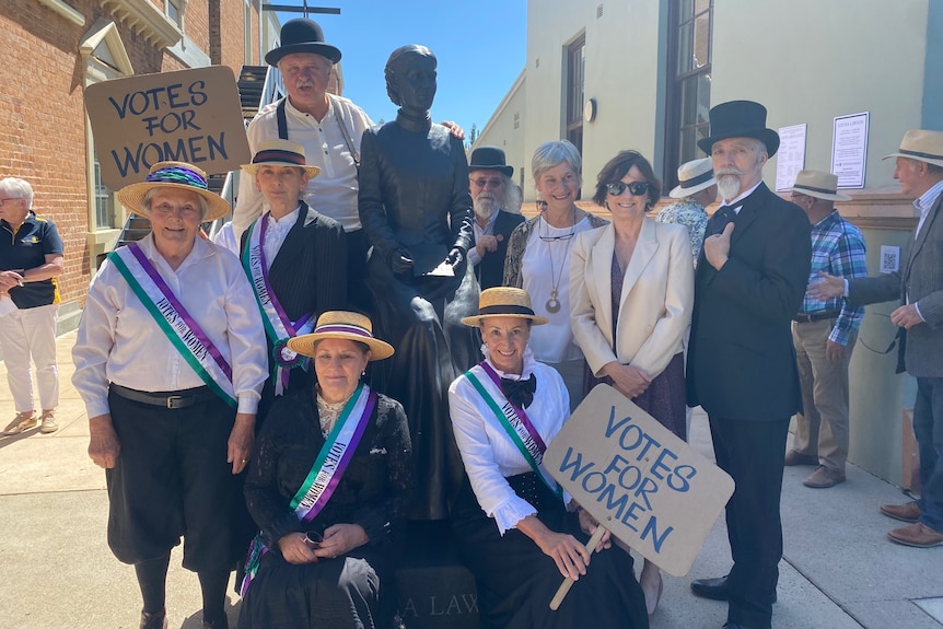 A crowd of people standing around a statue