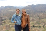 Jennifer and Siana wear jackets and smile in front of a mountain range in Peru.