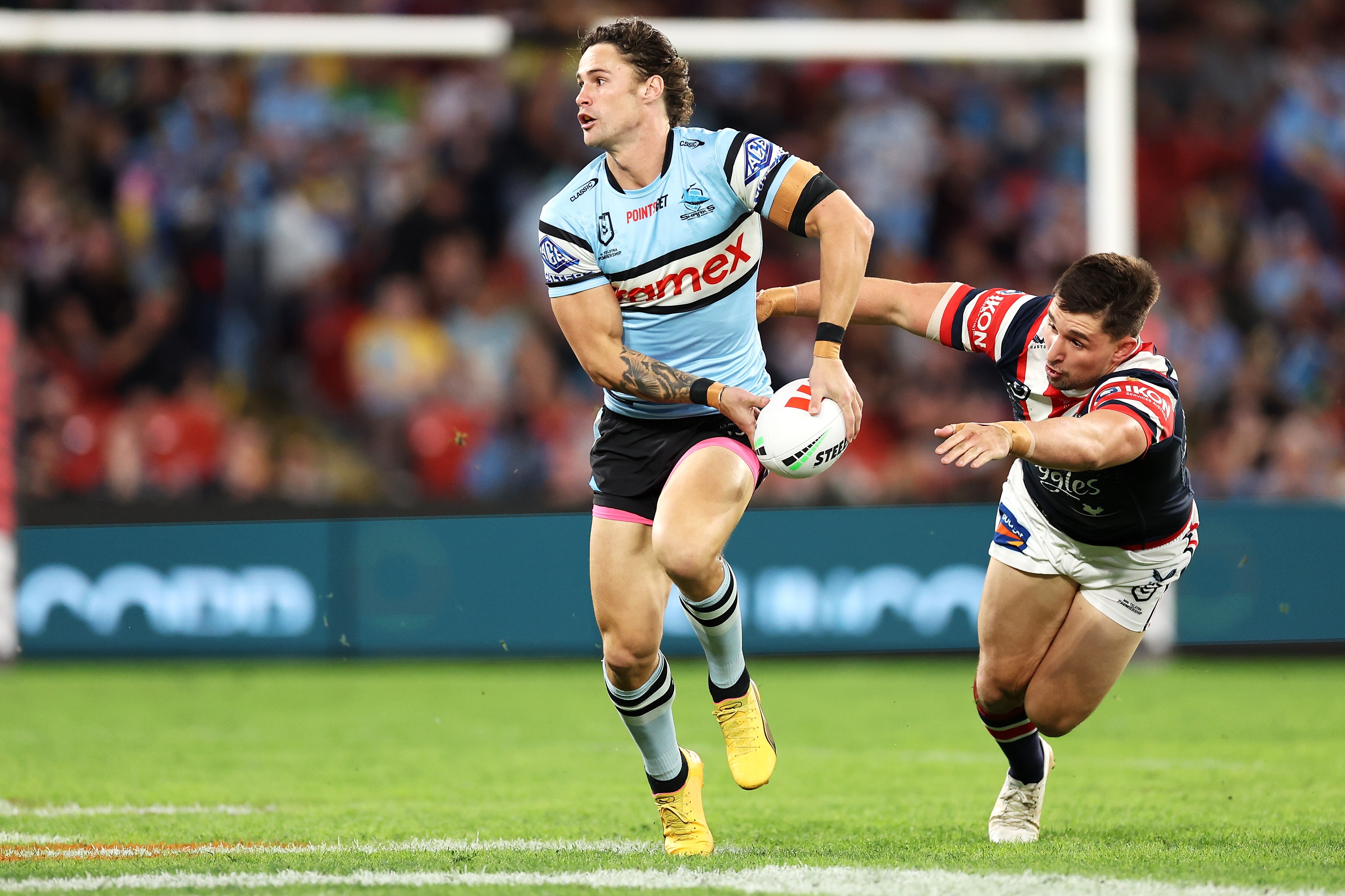 Nich Hynes of the Cronulla SHarks runs with the football as Sydney Roosters defender Victor Radley dives after him.