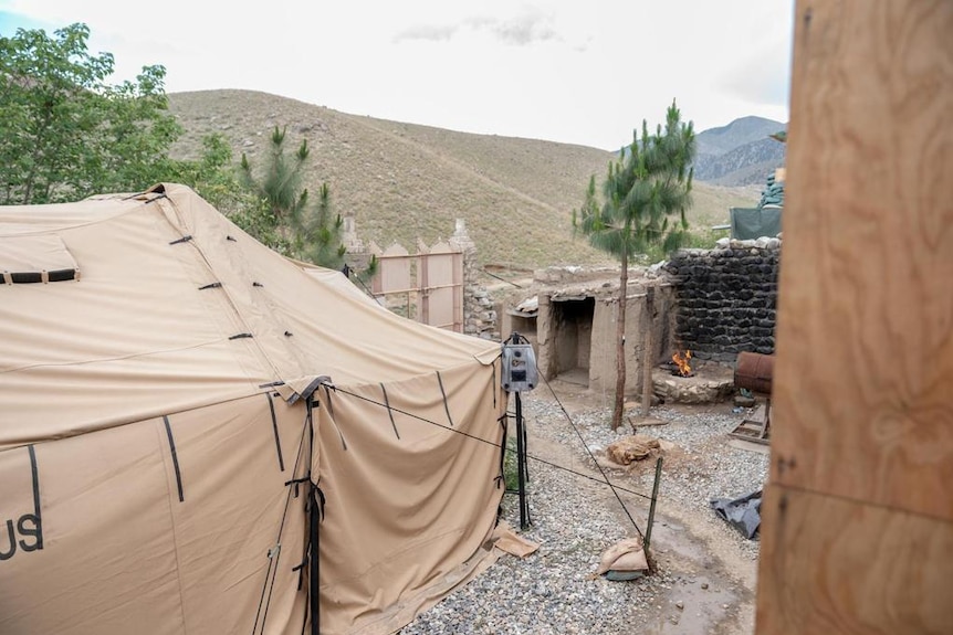 A military tent, protective wall and gravel floor forms a military outpost in the Afghanistan hills.