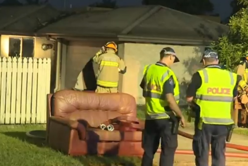 Firefighters and police at the scene of a blaze that gutted a Beerwah unit, with a couch outside on the street.