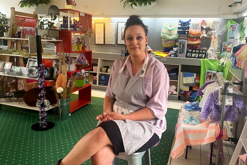 A woman sits on a stool in a shop
