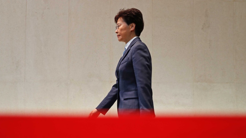 You see Hong Kong's Chief Executive Carrie Lam strut in a pant-suit behind a red tape.