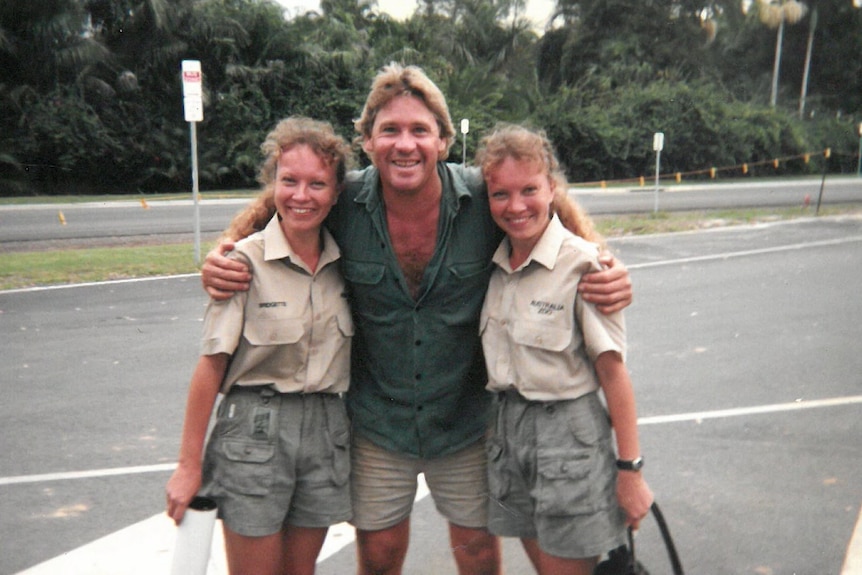 Two identical twins wearing khaki stand next to steve irwin in khaki