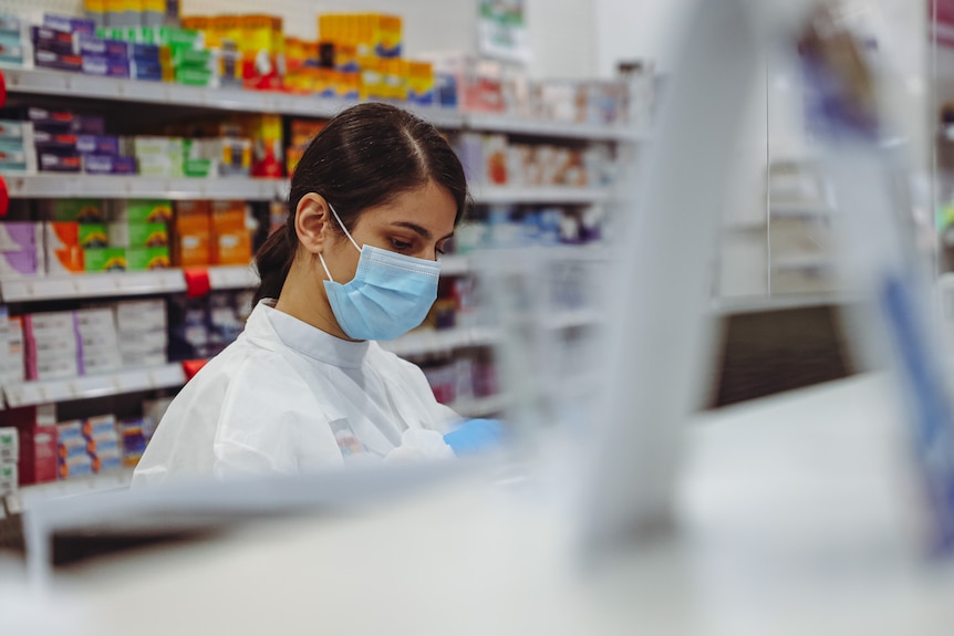 a woman wearing a mask working at a pharmacy