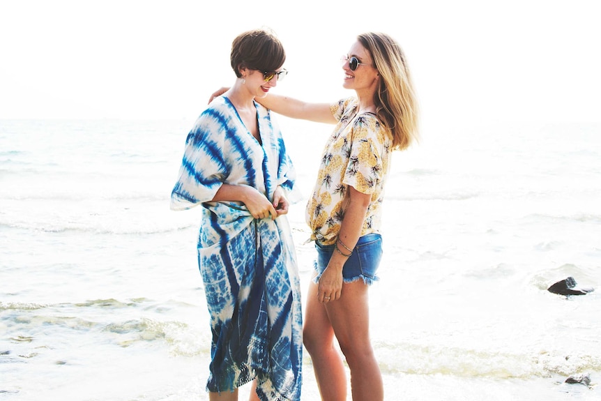 Two women stand together on the beach to depict dating without apps.