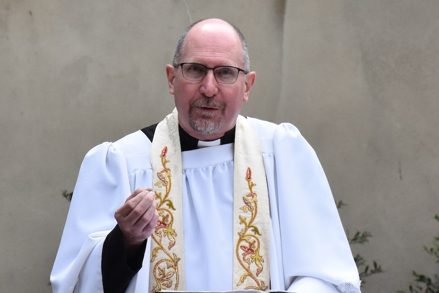 Father Hugh Kempster delivers a mass outside a church building.