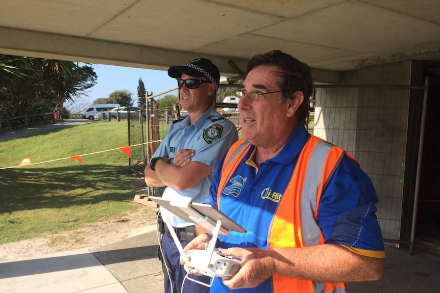 A police officer and another man with a drone remote control.