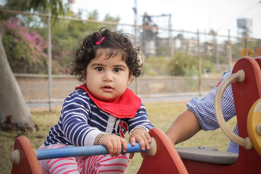 17-month-old Myra Chanaria sits on play equipment in a Mount Isa park.