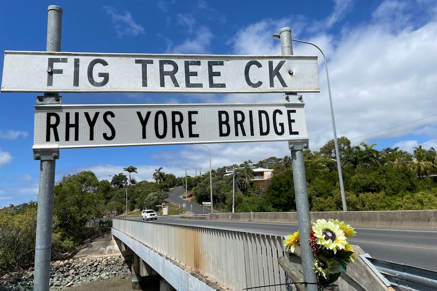 A sign reading 'Rhys Yore Bridge' in from of trees and a blue sky