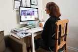 The back view of a woman working at a home desk. 