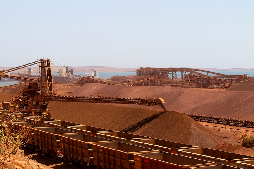 Large piles of red dirt, with blue ocean in the background.
