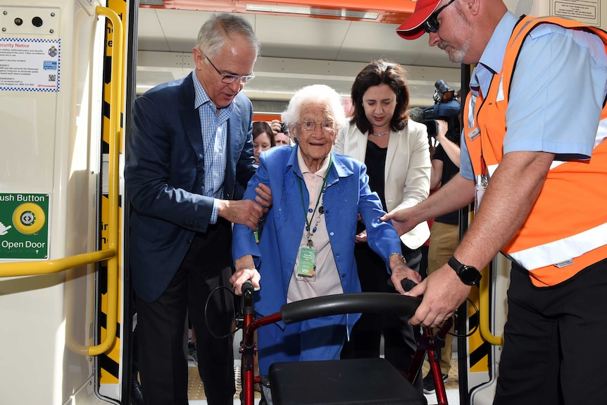 Australian Prime Minister Malcolm Turnbull (left) helps Frances Pearse onto train.