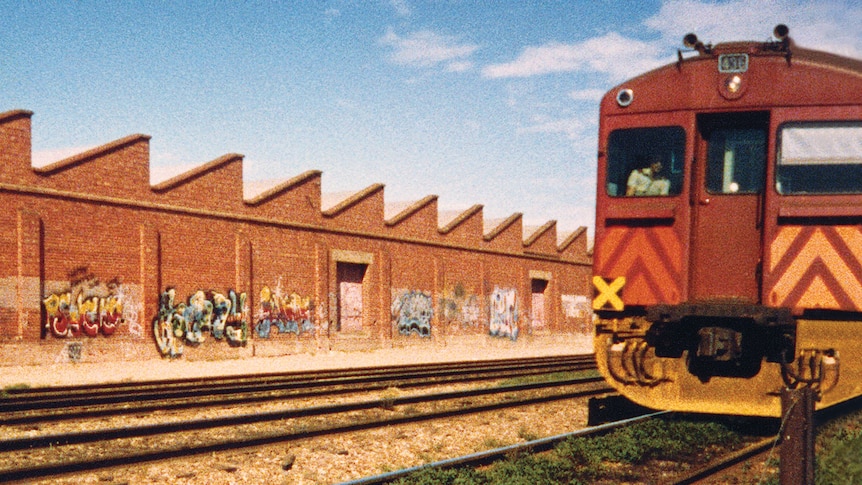 A train passes a wall with graffiti on it